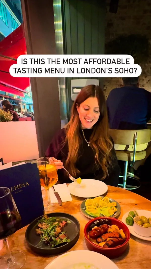 The video showcases Dehesa, a restaurant near Oxford Street in London's Soho, offering a tasting menu. It features various Spanish and Italian-inspired small plates, including chargrilled chorizo, ribeye steak, pil pil tiger prawns, Valencian arroz negro with baby squid and saffron aioli, and a pistachio and white chocolate dessert. The video primarily focuses on the food presentation and the overall dining experience.