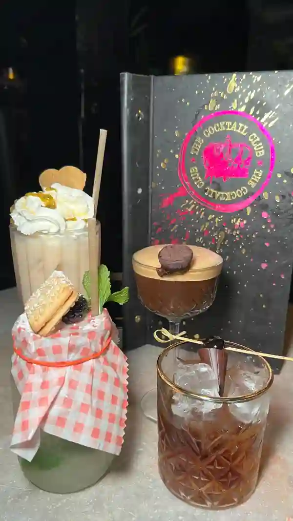 The video showcases The London Cocktail Club on Oxford Street. It highlights their bottomless brunches, cocktails, and entertainment.  Specific cocktails featured include the Truffletini (espresso martini with rum and chocolate truffle) and the Solero Sundae (a creamy, sweet cocktail). The video emphasizes the 2 for £12 cocktail deal during happy hour. The setting is a vibrant, dimly lit bar with a lively atmosphere.