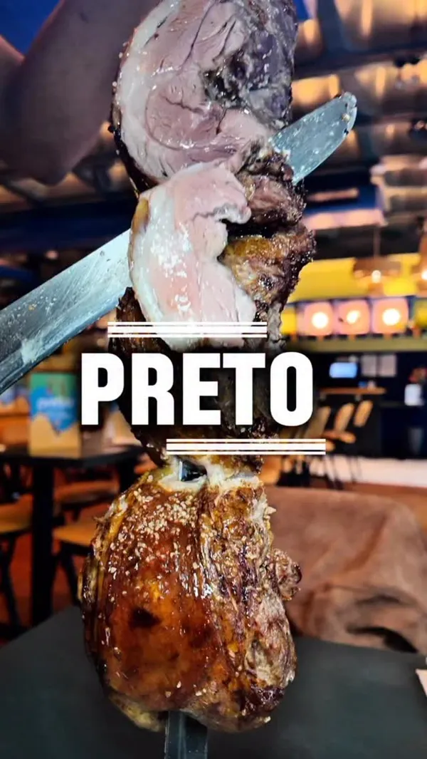 The video promotes Preto, an all-you-can-eat Brazilian steakhouse in London. It showcases a variety of meats being carved tableside from large skewers, including sirloin, rump, garlic beef, chicken, spicy sausages, and honey-glazed pork. The video also highlights the extensive buffet of hot and cold sides, salads, and sauces. Cocktails, specifically a 'Green Jamaican' and a Sangria, are featured, along with a chocolate dessert. The video follows the creators as they enjoy the full dining experience.