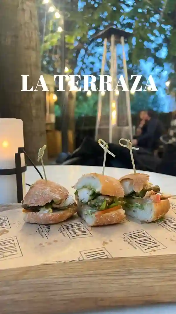 The video showcases La Terraza, an outdoor dining area of Iberica Restaurants. It features various food items such as bocadillos (small sandwiches), cheese and meat skewers, and cocktails. The presentation emphasizes the ambiance with string lights, outdoor heaters, and a DJ.  The main focus is on creating an inviting and lively atmosphere for alfresco dining.