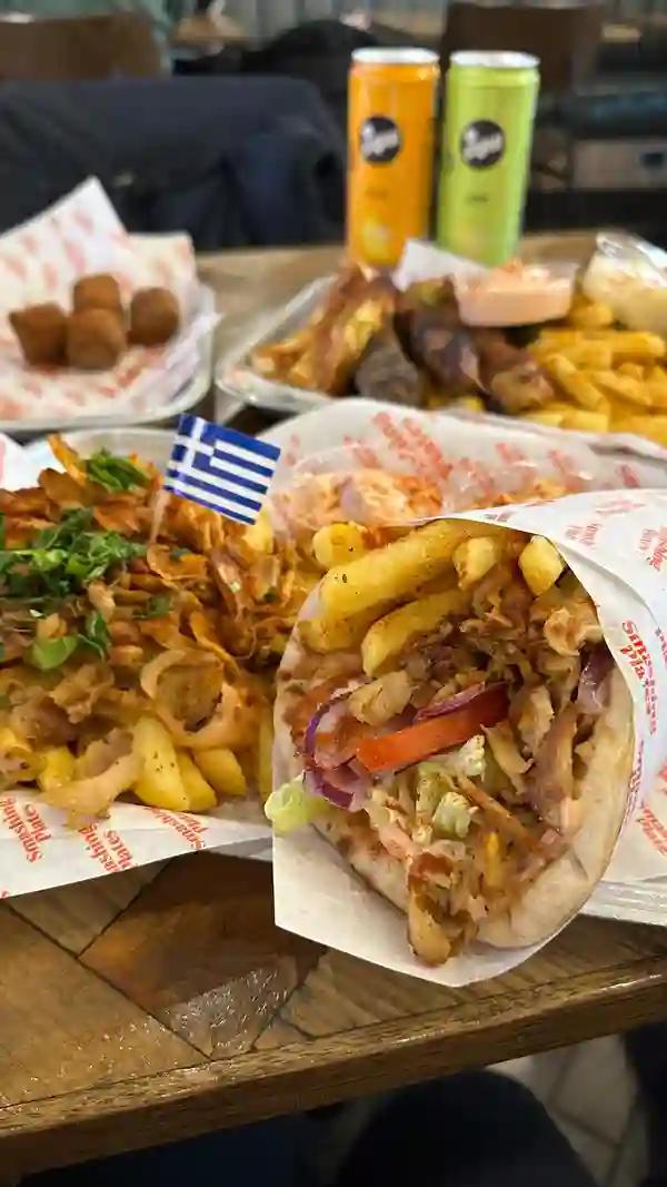 The video showcases a meal from Smashing Plates, a Greek restaurant in London. It features a large platter with various grilled meats (souvlaki, possibly kofta), halloumi fries, pita bread, and fries. Two small containers of sauces are visible. The setting appears to be the restaurant itself.  The food is presented on a large platter, highlighting its abundance. The video doesn't specifically mention dietary information.