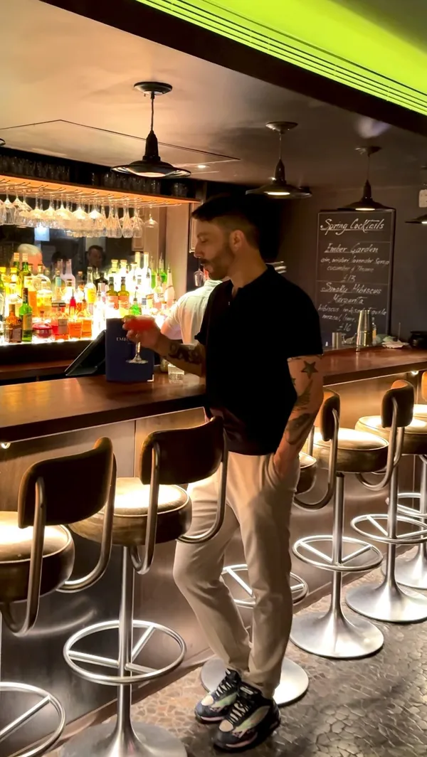 The video showcases a variety of cocktails at Ember Yard in Soho, London. It features close-ups of drinks being prepared and served, as well as shots of the bar's ambiance and patrons enjoying their drinks. The cocktails are presented in elegant glassware, garnished with fruit slices, and feature vibrant colors. There is no mention of dietary restrictions. The primary focus is on the bar's atmosphere and the unique cocktail creations.