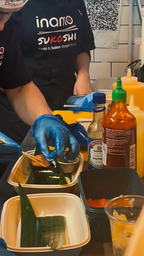 The video showcases a collaboration between James May's gin and Inamo Sukoshi restaurant. It features the preparation of two cocktails, scenes from a bar with neon signs and people, and various sushi dishes made with James May's gin. The restaurant's menu is also briefly shown.