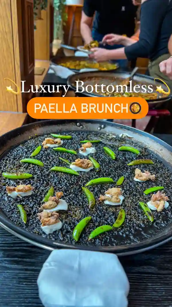 This video showcases a luxurious bottomless paella brunch experience at Arros QD, a Spanish restaurant in London.  The video starts with a close-up of paella, then transitions to showing the restaurant's interior, welcome cocktails, a selection of tapas, various paella options, and finally, several desserts. The food is presented beautifully with close-up shots and creative plating. No specific dietary information is provided.