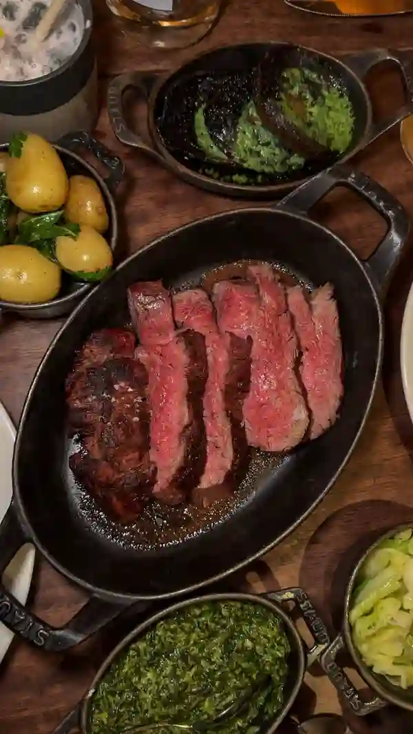 The video showcases a dinner experience at Hawksmoor Seven Dials in Covent Garden, London.  It features various dishes, including smoked salmon, scallops, a Chateaubriand steak (the main focus), various side dishes (potatoes, spinach, greens, mushrooms), and desserts (sticky toffee pudding, peanut butter shortbread). The food is presented elegantly, with close-ups emphasizing texture and color.  The setting is a high-end restaurant. The video also includes brief shots of drinks and the restaurant's ambiance.