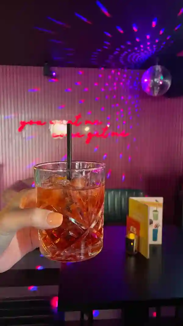 The video showcases the preparation and enjoyment of Negroni Sbagliato cocktails in a vibrant, dimly lit bar setting.  The cocktails are presented in short rocks glasses with ice and an orange peel garnish. The bartender expertly mixes the drinks, emphasizing the inclusion of Prosecco. The video focuses on the preparation and the celebratory atmosphere surrounding the cocktails, with minimal emphasis on any food items.  No specific dietary information is mentioned.