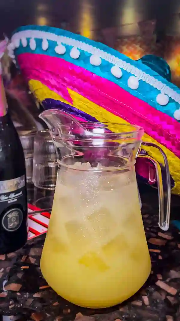 The video showcases a vibrant bottomless brunch event at Tequila Mockingbird in Charing Cross, London.  It features a variety of shots:  a large pitcher of margaritas, a bottle of Prosecco, pizza slices being eaten, people enjoying the party atmosphere including dancing, limbo, and wearing sombreros. The overall mood is energetic and fun.