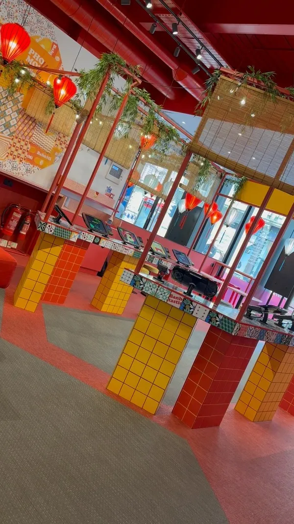 The video showcases Hop Vietnamese restaurant in London. It presents various dishes, including Banh Mi, noodle salads, Pho, vegan coconut curry, and prawn dumplings. The food is displayed in takeout containers and bowls, with a focus on vibrant colors and appealing textures. The restaurant's interior is also shown, featuring colorful decor, self-ordering kiosks, and a generally lively atmosphere.  The video highlights plant-based options and emphasizes the friendly service.