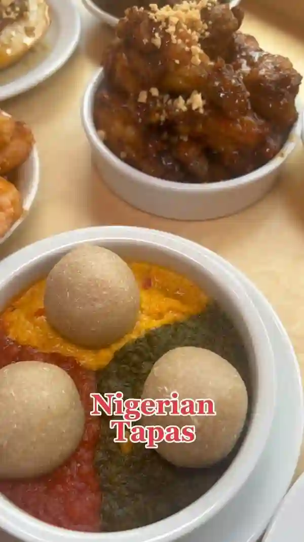 This video showcases Chukus, a Nigerian tapas restaurant in London.  It features various dishes, including spiced shrimp, chicken wings with a peanut topping, and a dish with fufu balls in a three-colored sauce. The video emphasizes the restaurant's brunch menu, highlighting a deal of six sharing plates and six drinks for £40 per person. The restaurant's interior, exterior, and several dishes are showcased.