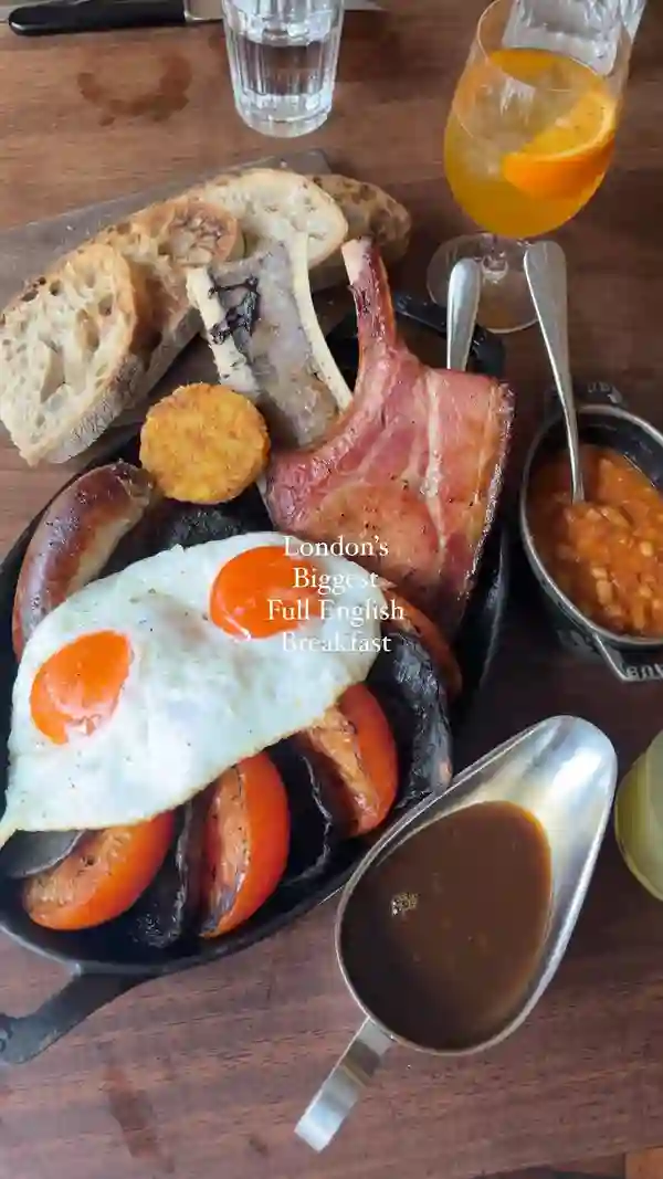 The video showcases a luxurious full English breakfast platter at Hawksmoor Restaurants, featuring items like a sugar-pit bacon chop, Victorian sausages, black pudding, hash browns, grilled bone marrow, baked beans, fried eggs, grilled mushrooms, and roasted tomatoes. The breakfast is served on a large, black skillet, and the video highlights its generous portions and appetizing presentation.  The video primarily focuses on presenting the full English breakfast and its various components.