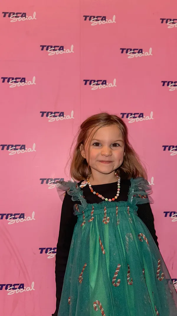 This video showcases Toca Social, a venue at London's O2 arena. It features family members playing interactive games, enjoying festive food (including bao buns, fried chicken, and snacks), and drinks. The lighting is a blend of bright and dim areas, highlighting the different zones of the establishment.  The festive theme is apparent with a large Christmas tree in the background of some scenes. 