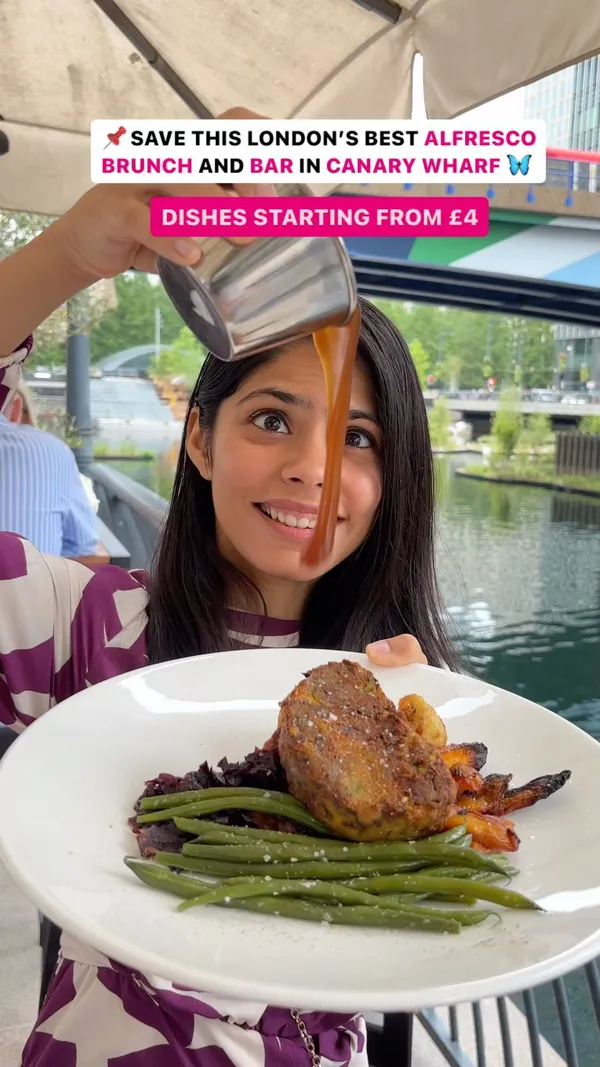 The video showcases a variety of food and drinks available at The Address restaurant in Canary Wharf, London.  The setting is an outdoor seating area overlooking a canal. Food items include a Sunday roast (meatloaf, roasted vegetables, gravy), pancakes with bananas and a caramel sauce, French toast with berries and yogurt, avocado toast, and a burger with fries. The presentation focuses on visually appealing food arrangements and close-up shots to highlight textures and details. No specific dietary information is provided. The main focus is on presenting the food and drinks and creating a positive atmosphere about the venue.