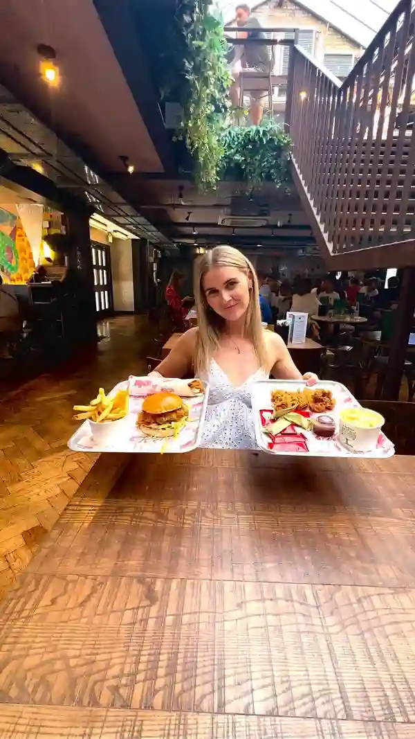 The video showcases Butchies fried chicken restaurant in London. It features various dishes including a fried chicken burger, a fried chicken wrap, fries, and mac and cheese. The food is presented on trays and in individual containers. The video focuses on the food's visual appeal and emphasizes its affordability. No dietary information is explicitly stated.