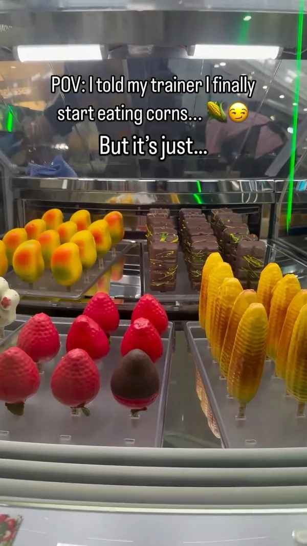 The video showcases desserts from a gelato shop called Snowflake Gelato. It begins with a shot of a display case filled with novelty desserts shaped like fruits and corn. The main feature is the 'Snowcob,' a corn-on-the-cob-shaped gelato pop. The video shows it being drizzled with caramel sauce, and a bite is taken to reveal the creamy ice cream interior. A layered purple and green ube drink with a whipped topping is also featured.