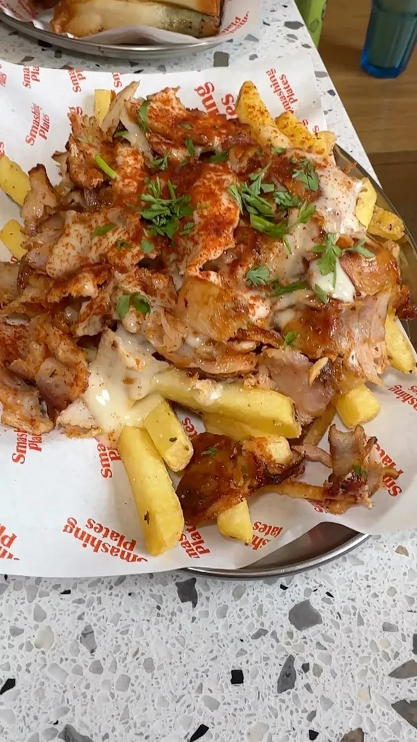 This video showcases a visit to Smashing Plates, a Greek restaurant in London Bridge. It features various dishes including a Greek Loaded Salad, Grilled Feast (with various grilled meats, fries, and pita bread), Unorthodox Fries, Spinach and Feta Cheese Rolls, Pittanuts (fried pita bread with honey), and Epsa fizzy drinks. The video highlights the generous portions, the quality of the meats, and the variety of dips.  The restaurant's interior and ordering process are also shown.