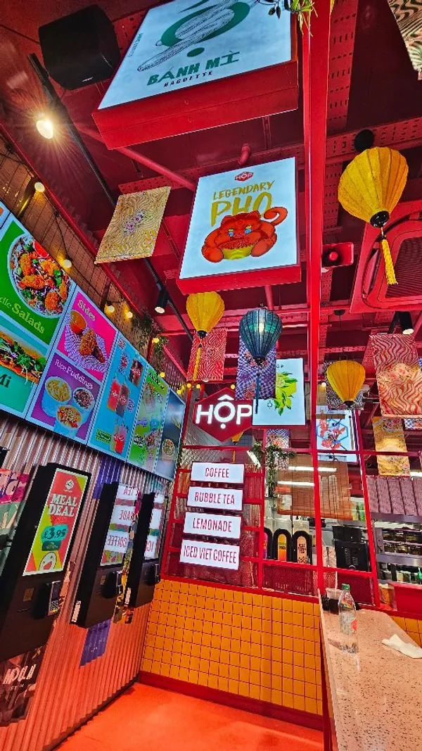 The video showcases a family's visit to HOP Vietnamese restaurant in London's Bond Street Tube station.  It features various food items including Banh Mi, a HOP Box with pork riblets, beef brisket Pho, fried chicken dippers, vegetable dumplings, bubble tea, and Vietnamese iced coffee.  The food is presented in disposable containers and the video includes shots of the family enjoying the meal. Halal, vegan and gluten-free options are mentioned. The main focus is on the food and the family's experience.