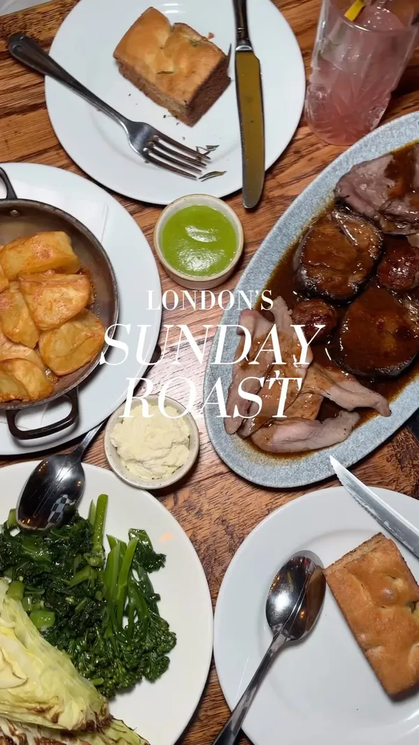 The video showcases a Sunday Roast for Two at Ember Yard restaurant in London.  It features various dishes, including homemade focaccia, 35-day dry-aged sirloin, Hampshire x Duroc presa, slow-cooked feather blade, Iberico pork fat roast potatoes, chargrilled cabbage and greens, Granny Smith apple puree, horseradish Chantilly, and rich red wine gravy. The presentation focuses on the appealing visual aspects of each dish, with close-ups and overhead shots. No specific dietary information is provided. The main focus is on the meal itself, with shots of the restaurant's interior also included.