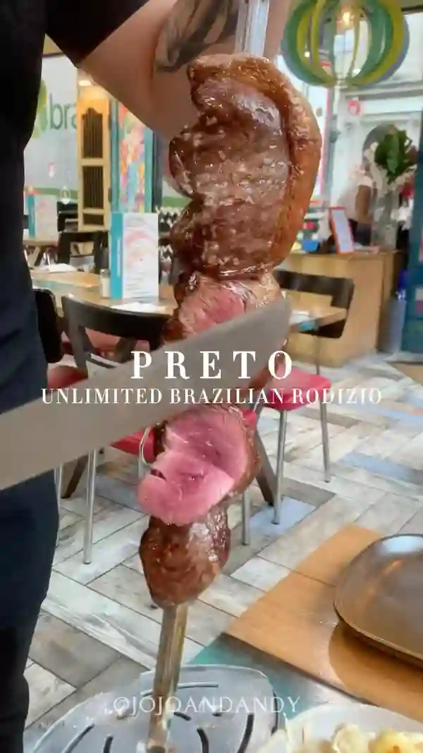 This video showcases Preto Unlimited Brazilian Rodizio, a Brazilian steakhouse in Angel, London. It highlights the all-you-can-eat meat selection, served table-side, and features various cuts of grilled meats, such as Picanha and bacon.  The video also shows the self-service salad bar offering a variety of side dishes, including rice, beans, salads, and cheeses. Finally, it shows a close-up of a caramel flan dessert. The presentation emphasizes the visual appeal of the food and the restaurant's ambiance.