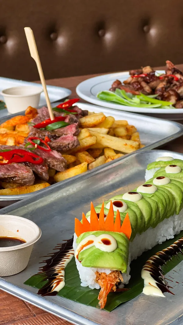 The video showcases Inamo Sukoshi restaurant on Oxford Street, London. It features various dishes: crispy aromatic duck (served with pancakes, cucumber, and spring onion), Asian-style steak with fries, a dragon roll (tempura shrimp with avocado), crunchy salmon and avocado uramaki, and two Aloe Vera sparkling drinks. The presentation emphasizes vibrant colors and creative plating, with sushi rolls artfully arranged.  The main focus is on the food and drink, highlighting the restaurant's menu.