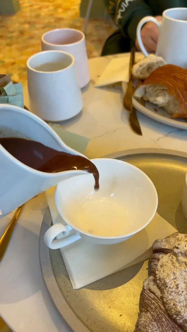 This video showcases the Parisian hot chocolate at Valaria Bakery in Glasgow. The bakery's interior and various pastries are also highlighted. The video emphasizes the rich, thick texture of the hot chocolate and the buttery, flaky quality of the pistachio croissant, which is presented with a marzipan-like pistachio paste filling. The process of dipping the croissant into the hot chocolate is shown. No dietary information is explicitly mentioned.