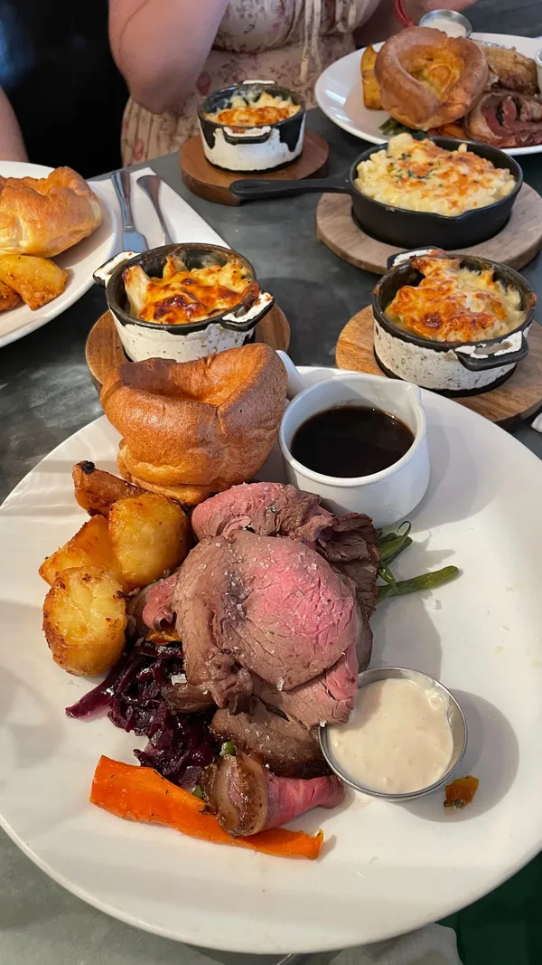 The video showcases a meal at No.32 The Old Town restaurant in London. It features various dishes, including salt pig nduja and cheddar croquettes, roast beef with horseradish cream, the mixed roast, macaroni and cheese, apple and raspberry crumble, tiramisu, and raspberry sorbet. The food is presented in visually appealing ways, highlighting attractive plating, rich colors, and textures. Dietary information is implicitly shown through the various options available. The video's main focus is on showcasing the meal and the overall dining experience.