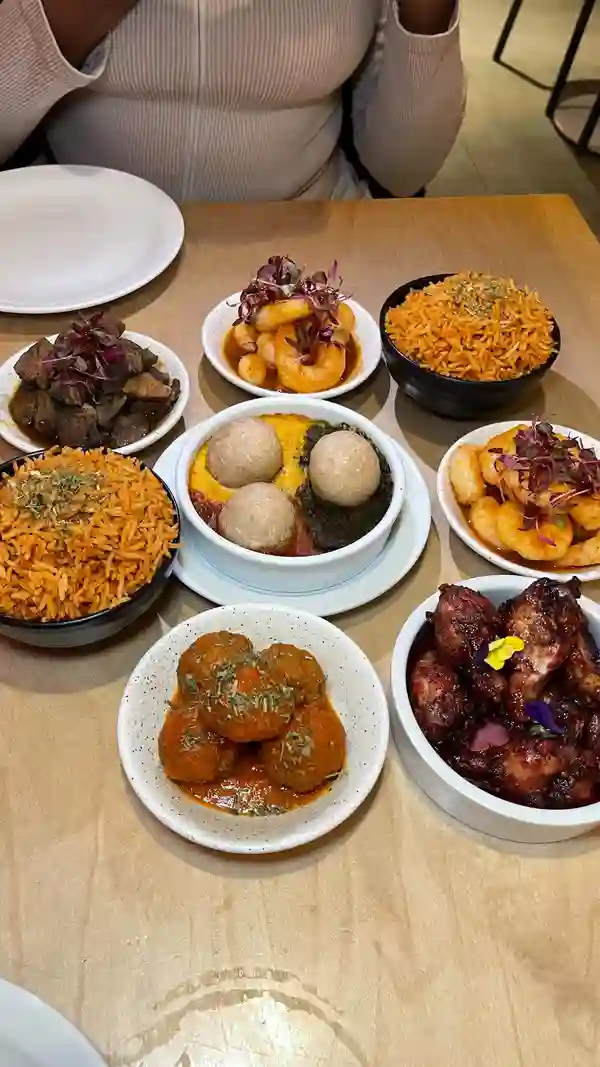 The video showcases Chuku's, London's first Nigerian tapas restaurant. It features a variety of Nigerian dishes presented tapas-style, including Jollof rice, an egusi bowl, zobo wings, lamb ayamese, and a plantain waffle with ice cream. The food is presented in small bowls and plates, attractively arranged on a table. The video focuses on the food itself, with close-up shots highlighting the textures and colors of each dish.