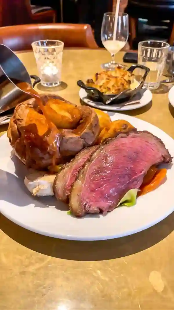 This video showcases a Sunday roast dinner at Hawksmoor Liverpool.  The video features close-ups of the food, including the slow-roasted native breed rump, beef dripping roast potatoes, Yorkshire pudding, various vegetables, and sides such as cauliflower cheese and stuffing. The presentation emphasizes the quality and richness of the food.  The video also shows cocktails and Sticky Toffee Pudding for dessert. No dietary information is explicitly stated.