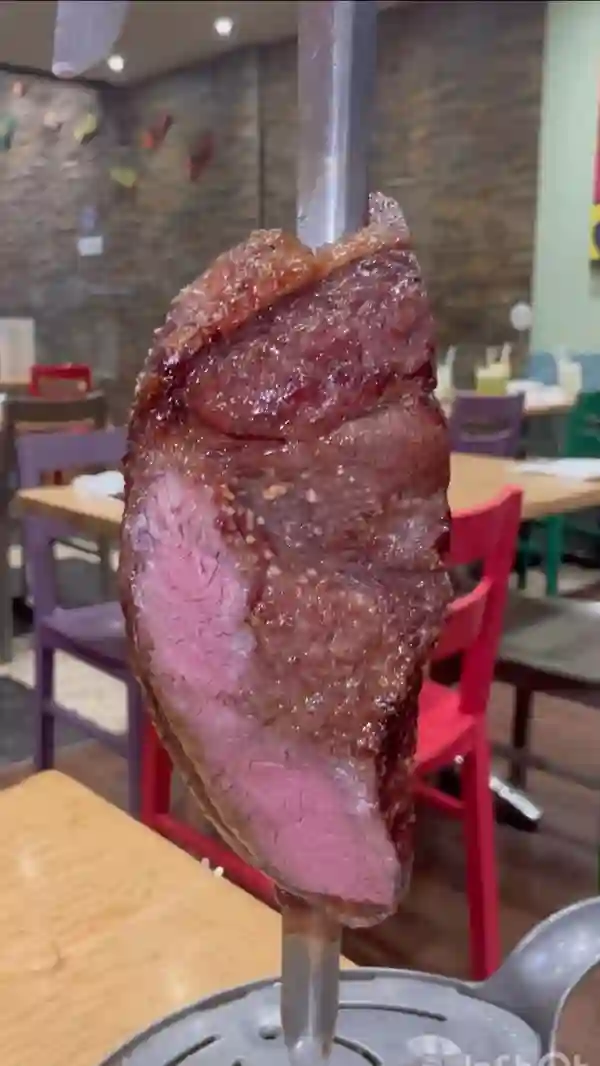 The video showcases a visit to Preto restaurant in London, a Brazilian steakhouse.  It features various cuts of meat, including steaks and chicken, served on skewers tableside. The buffet includes a variety of side dishes like salads, roasted vegetables, and fried snacks.  Cocktails are also presented. The video emphasizes the restaurant's all-you-can-eat concept and lively ambiance.