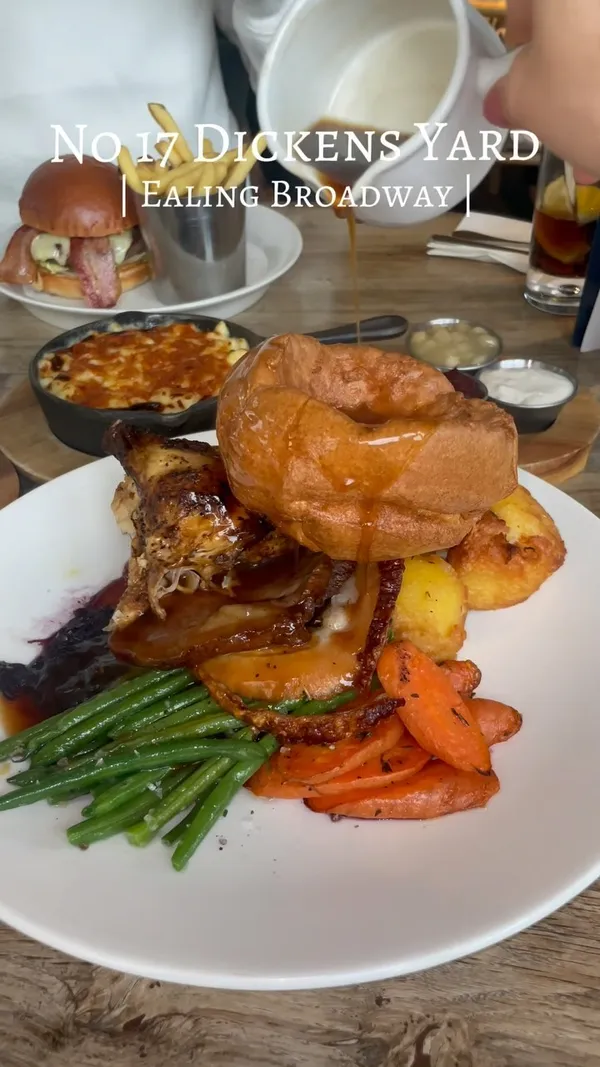 The video showcases a meal at No 17 Dickens Yard in Ealing Broadway. The food includes a mixed roast, a burger, mac and cheese, brioche pain perdu, and tiramisu. The presentation is visually appealing, with various angles and close-ups highlighting the food's textures and colors. No dietary information is provided. The main focus is on showcasing the restaurant's food offerings.