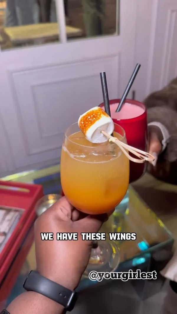 This video showcases The Little Scarlet Door, a bar in London. The video highlights their cocktails (including mocktails), bar food (teriyaki wings, bean dip hummus, and a truffle cheesesteak toastie), and a downstairs area with arcade games and a DJ. The food and drinks are presented in an aesthetically pleasing manner, with focus on their visual appeal.