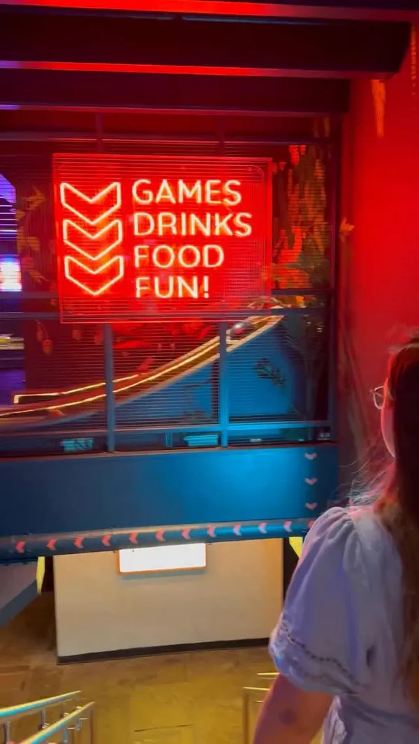 This video promotes 'Bat & Ball', an entertainment bar in Covent Garden, London. It showcases the venue's various activities, including electronic darts, private karaoke, shuffleboard, and indoor mini-golf. The video also highlights their food and drink offerings, featuring shots of Korean-style wings, loaded fries, a pepperoni pizza, and cocktails. The overall atmosphere is portrayed as energetic and fun, with neon lighting and upbeat music, positioning it as an ideal spot for a night out with friends.