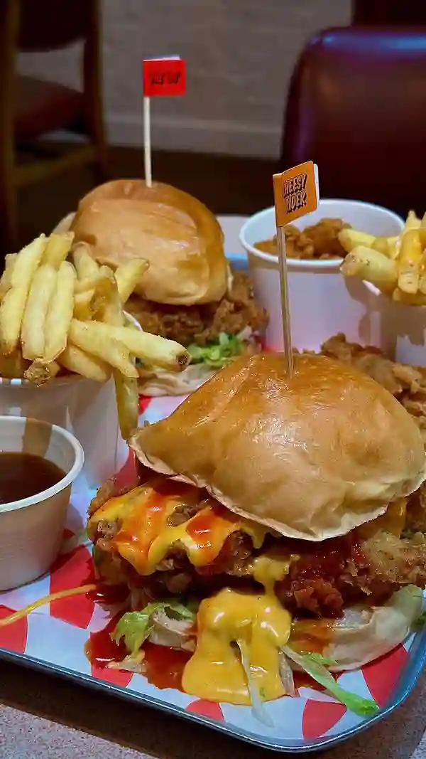 The video showcases a meal from Butchies Fried Chicken in London.  The food includes chicken burgers (Cheesy Rider and OG), chicken tenders, popcorn chicken, chips, and cheese fries.  The presentation emphasizes abundance and focuses on the food's textures and colors.  The main focus is on a meal showcase, highlighting the new gravy option. No specific dietary information is provided.