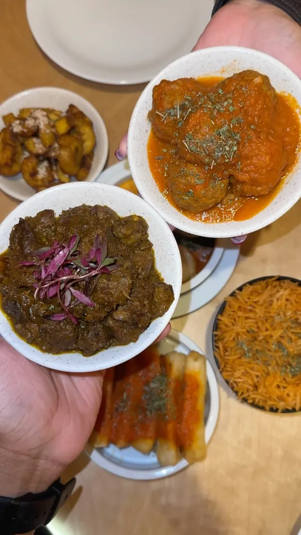 The video showcases a meal at Chuku's, a Nigerian tapas restaurant in London.  It features various dishes, including Lamb Ayamase, Jollof rice, Egusi bowl, Suya meatballs, Cassava & ata din din, Dodo (fried plantains), and a Yam brownie.  Drinks include Zobo and Chapman punch. The presentation focuses on overhead shots of the food, highlighting colors and textures.  No specific dietary information is provided.