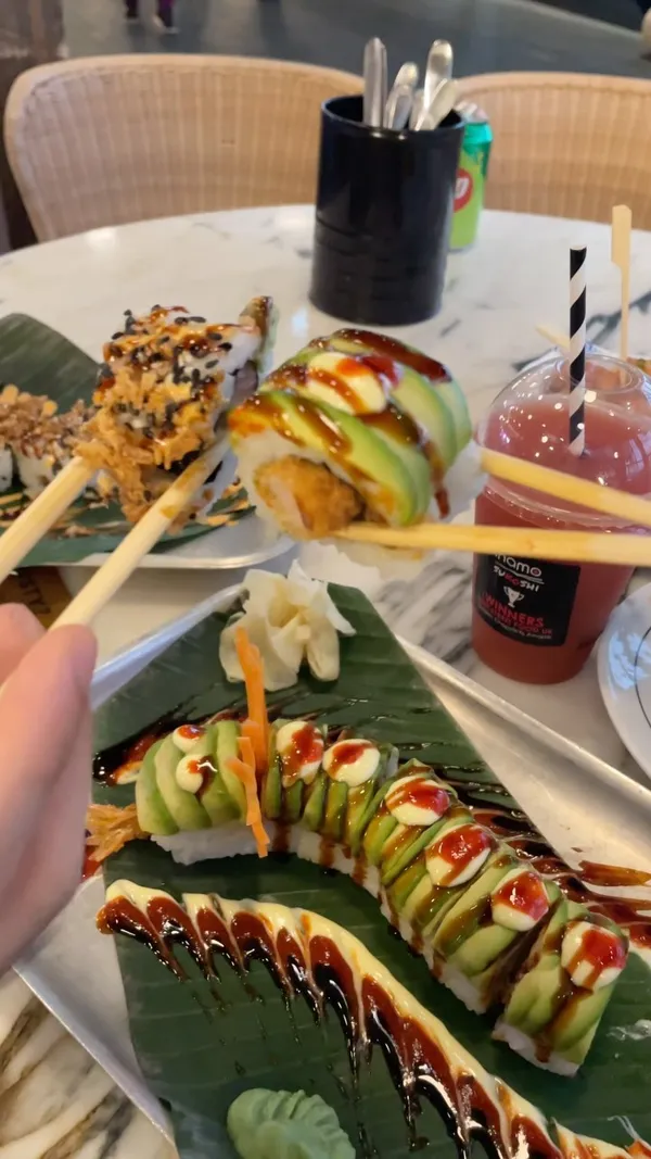 The video showcases Inamo Sukoshi, a restaurant located in Canary Wharf Market Halls. It features various dishes, including bang bang cauliflower, veggie ramen, and uniquely designed dragon rolls. The presentation is visually appealing, with a focus on the food's aesthetics. The video mentions that the restaurant doesn't offer halal meat options, but there are vegetarian and seafood choices. The main focus is on showcasing the food and the ambiance of the restaurant.