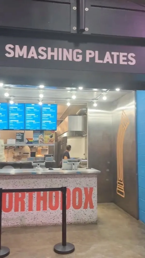 The video showcases a woman's food review of Smashing Plates, a street food establishment.  The items featured are: a Chicken Souvlaki wrap (chicken, chips, salad, mustard mayo in a pitta bread); a Lamb and Beef Souvlaki box (lamb and beef skewers, chips, salad, pitta bread, tzatziki mayo); and Pittanuts (fried pitta bread with cinnamon and maple syrup). The presentation focuses on close-ups of the food and the woman's reactions. No specific dietary information is provided.