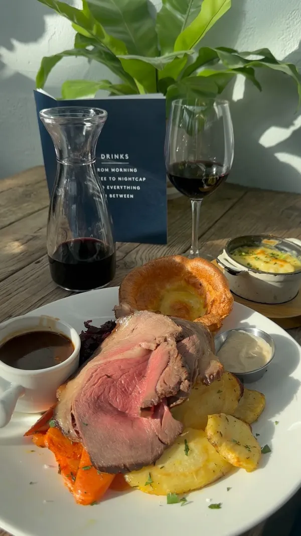 This video showcases a variety of food and drinks available at The Address restaurant in Wimbledon. It begins with a couple enjoying wine, then shows a sequence of appetizers, including braised leek and cheddar croquettes and buttermilk fried chicken tenders. The main course featured is a roast beef with vegetables, Yorkshire pudding, and cauliflower cheese. The video concludes with desserts (Banoffee pie cheesecake, sticky toffee pudding) and cocktails.  All dishes are visually appealing and well-presented. No dietary information is explicitly mentioned.