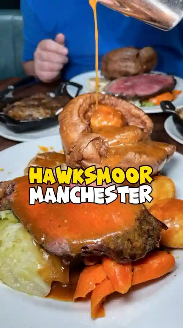 The video showcases Hawksmoor Manchester, a steakhouse known for its Sunday roast. The setting is the restaurant itself, with various shots of the interior, including the bar area. The food items shown include a roast beef dinner with Yorkshire pudding, roasted potatoes, carrots, cabbage, bone marrow gravy, cauliflower cheese, Hawksmoor stuffing, and sticky toffee pudding with clotted cream. Presentation-wise, the dishes are visually appealing, with the focus on the rich colors and textures of the food. The primary focus is to highlight the roast beef dinner and other menu items, accompanied by a cocktail-making sequence.  No dietary information is clearly stated.