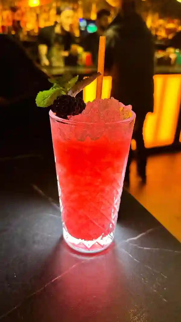 The video showcases The Cocktail Club in Birmingham, highlighting their Friday Night Live event.  It features various cocktails, including a vibrant pink drink (possibly a daiquiri or bramble), an orange-hued cocktail in a coupe glass, and a clear shot.  The cocktails are presented attractively, with garnishes like fruit slices, mint, and small umbrellas. The setting is a trendy bar with dim lighting and live music. The main focus is on the event, cocktails, and the atmosphere. No dietary information is explicitly provided.