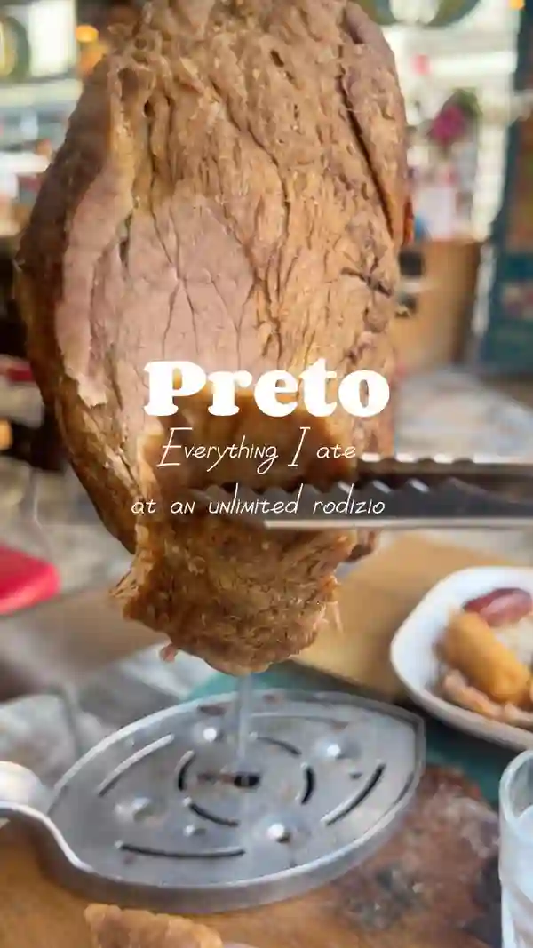 The video showcases Preto Restaurant, a Brazilian steakhouse, focusing on its all-you-can-eat rodizio experience. It highlights the restaurant's buffet featuring various Brazilian dishes like feijoada, feijao tropeiro, pão de queijo, and salads. The main focus is on the extensive selection of 15 different grilled meats, including beef, chicken, and pork, offered through a table-side service.  The video also shows the 'more please' and 'I'm full' cards used to manage the meat service and concludes with a dessert, pudim.