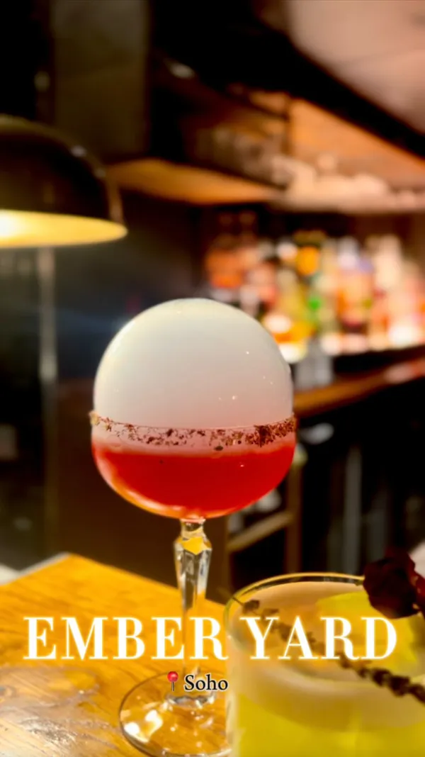 The video showcases Ember Yard, a restaurant with a hidden cocktail bar. It features various cocktails: a smoke-infused hibiscus margarita, a classic Negroni, a Passion Yard, an Ember Garden, and a bartender's special.  The cocktails are presented in stylish glassware with garnishes.  The video also briefly shows a bowl of mixed nuts and a fried zucchini flower dish. The main focus is the cocktails, highlighting their unique presentation and the bar's ambiance.
