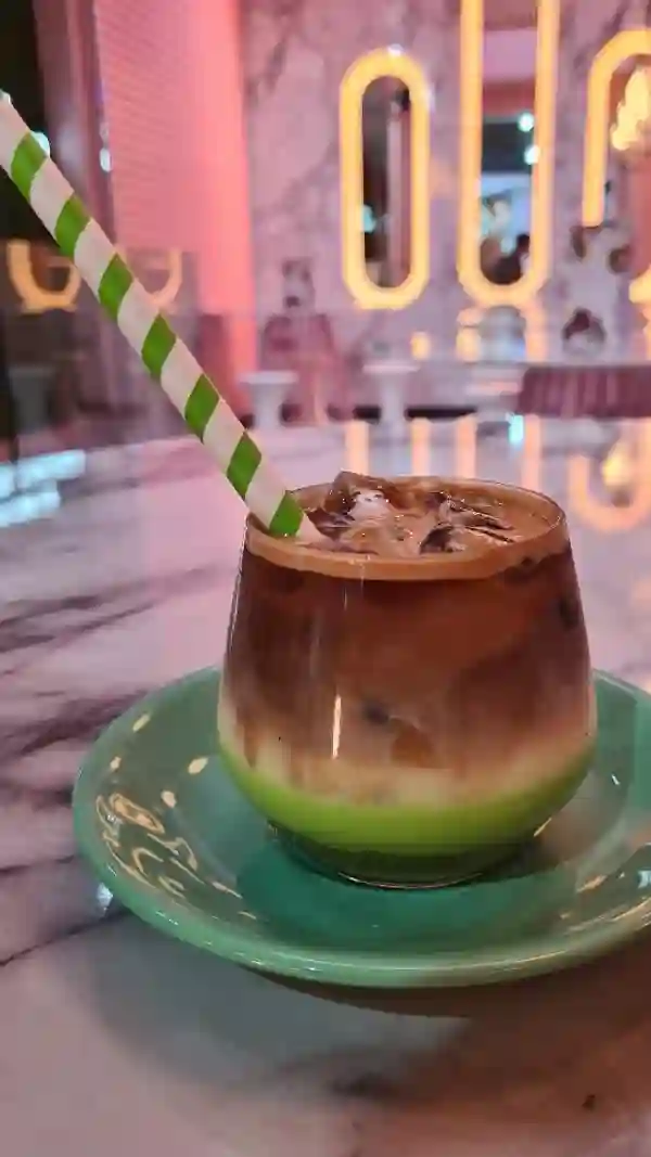 The video showcases Snowflake Gelato, a dessert parlour in London. It features an Iced Pistachio Latte, various gelato flavours (including those with chocolate, nuts, and sprinkles), and different types of ice cream cones. The presentation focuses on the visually appealing layering of the latte, the vibrant colors of the gelato, and the variety of toppings on the cones. The setting appears to be a modern, brightly lit gelato shop.