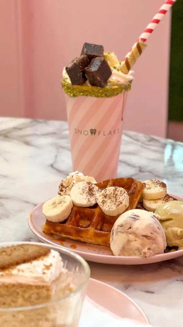 The video showcases Snowflake Gelato in Soho, London. It features three desserts: a milk cake with Lotus biscuits, banoffee waffles with gelato, and a pistachio brownie sundae milkshake. The presentation is visually appealing, with close-up shots highlighting textures and colors. No dietary information is explicitly mentioned. The main focus is a delicious dessert showcase.