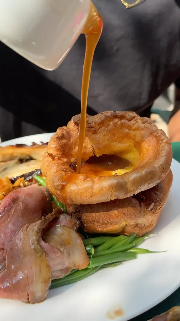 The video showcases a Sunday lunch at No.1a Duke Street in London. It features a variety of food items, including a mixed roast with beef, chicken, and pork, Yorkshire puddings, gravy, green beans, and dauphinoise potatoes. The presentation is visually appealing and highlights the abundance of food.  The video focuses on the meal itself and the experience of enjoying a large Sunday roast.