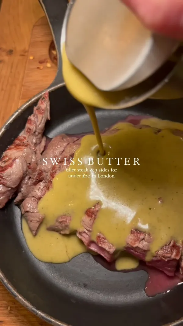 This video promotes Swiss Butter, a restaurant in London. The video showcases the restaurant's interior and exterior, and the food they offer, including steak with Swiss butter sauce, fries, salad, and baguette. The video also shows the molten chocolate cake dessert. The main focus is on the steak dish and the Swiss butter sauce.