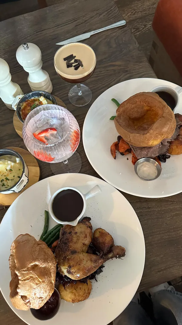 The video showcases a dining experience at a restaurant called "The Address." It features various food and drink items including cocktails (passion fruit and a coffee-based drink), fried calamari, pasta, roast beef with Yorkshire pudding, and a roast chicken dinner. The food is presented attractively on plates, and the restaurant's ambiance is also shown. 