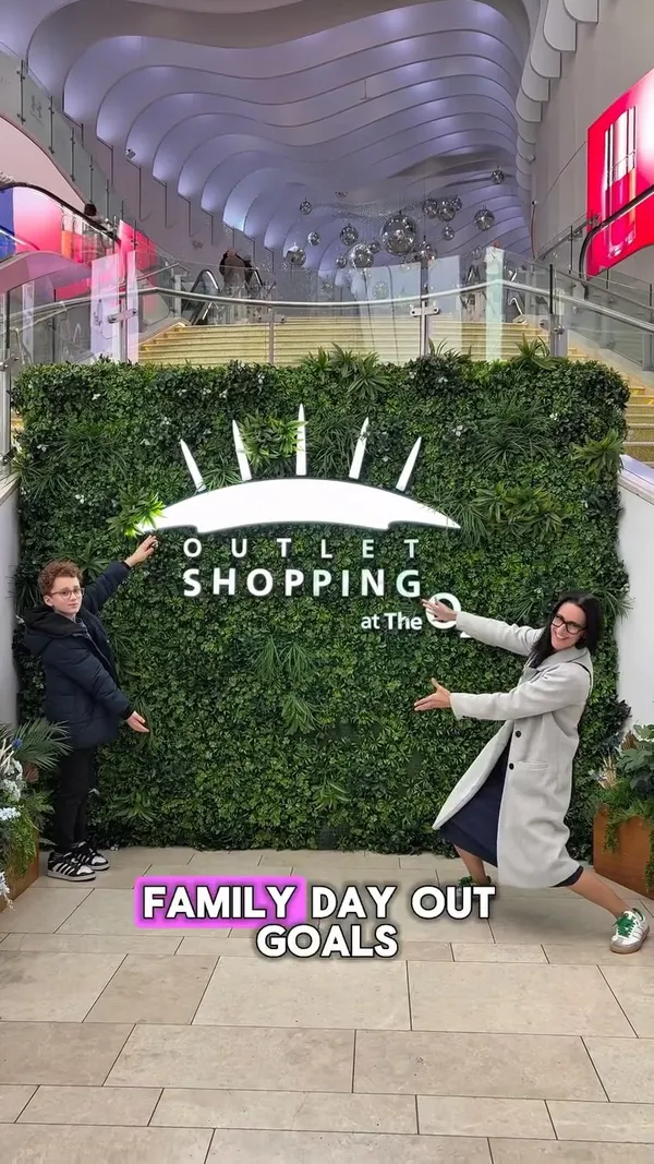 A fast-paced montage video showcasing a family's day out at The O2 in London. The video follows them as they visit various shops and attractions, including a Pop Mart vending machine, the Lindt chocolate store, a hat shop, and an Adidas outlet where they find a deal on trainers. They also stop for food at KFC, have dessert at Snowflake Gelato, and participate in an activity at the Clip 'n Climb indoor climbing centre. The video concludes with the mother trying on clothes at 'all good things' and a final shot of their shopping bags.