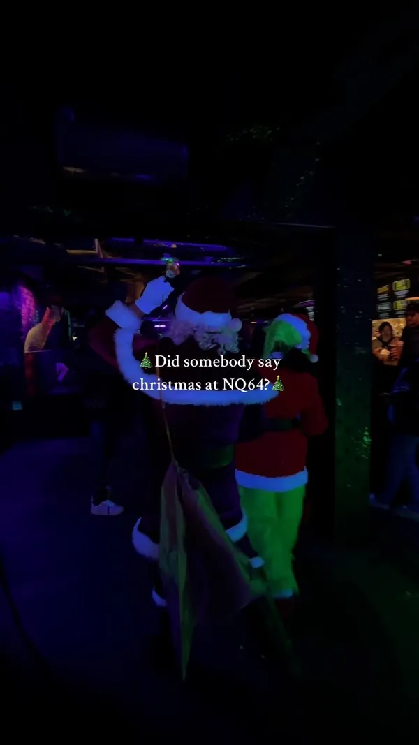 This TikTok video showcases NQ64 Arcade Bar in Manchester, UK, during their Christmas festivities.  The video uses quick cuts to show various aspects of the bar, including their decorated terrace, cocktails, games, and Christmas-themed decorations.  There is music playing in the background, and text overlays repeatedly ask, "Did somebody say Christmas at NQ64?" The video emphasizes the festive atmosphere and the bar's offerings.