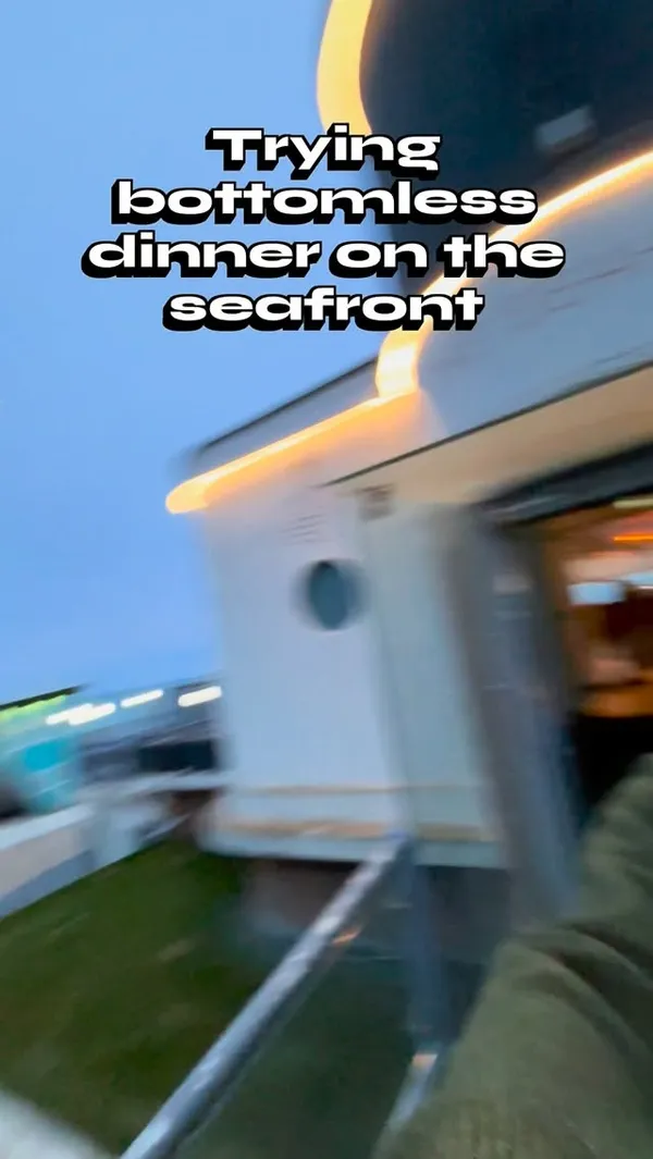 The video showcases a bottomless dinner experience at The Seahorse restaurant in Brighton. It begins with the creator arriving at the seafront venue, then shows the stylish interior and bar. The experience includes complimentary snacks like focaccia with pesto, popcorn, nuts, and olives, alongside cocktails (Margarita, Espresso Martini). The main courses featured are battered fish and chips and a Sri Lankan coconut curry. The video also highlights the variety of drinks available, including rosé wine and Aperol Spritz, and concludes with shots of two desserts: a green panna cotta-style dish and a chocolate lava cake with ice cream.