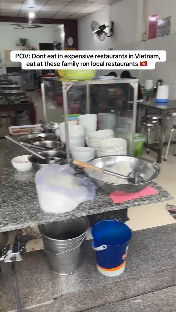 A short video showcasing a meal at a local, family-run Vietnamese restaurant. It begins with a view of the restaurant's interior, then shows a close-up of a bowl of Bún bò (Vietnamese beef noodle soup) with beef, blood cake, and green onions. A person is shown pouring tea, and the full meal is displayed with side dishes of fresh bean sprouts and herbs. The video concludes with a shot of the empty bowl and the restaurant's exterior signage.