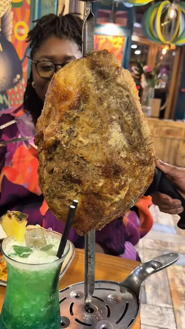 The video showcases an "all you can eat" Brazilian BBQ experience at Preto restaurant in Central London for £36. It begins by showing large skewers of various meats being carved at the table. The video then guides viewers through the buffet section, which includes a wide array of hot and cold sides like fried banana, chicken croquettes (coxinha), fried cassava, salads, garlic bread, and various stews. The main feature is the continuous table-side service of different meats, including beef, chicken wings, lamb, and pork, carved directly onto the diners' plates. The video also shows the diners' reactions, the restaurant's ambiance, and some cocktails. It concludes with a look at the dessert menu and a final shot of meat being carved.